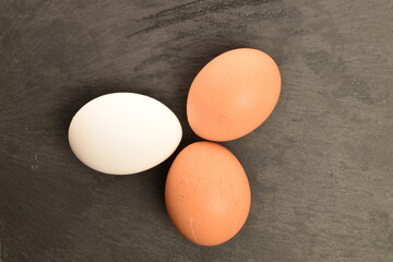 Three chicken eggs, close-up, on a slate board.