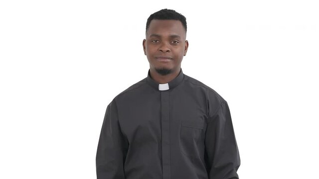 Portrait of handsome African priest patting his chest by hand, speaking something expression respect and appreciation isolated on white background