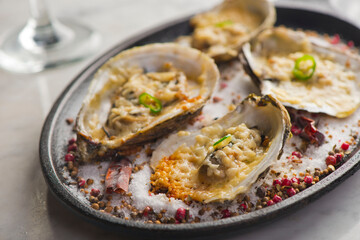 Oysters Rockefeller. Oysters topped with cheese, cream, garlic onions oven baked and garnished with fresh diced jalapeños. Classic American restaurant or French bistro appetizer.