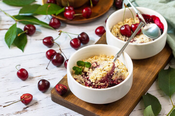 Homemade summer dessert. Cherry crumble in baking dish on a wooden tabletop.