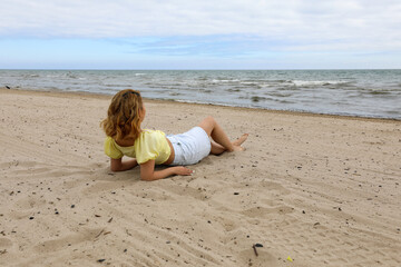 Fototapeta premium Young woman relaxing on beach. Woman taking a break to enjoy the view of the lake