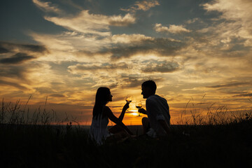 Plakat Young couple enjoying relaxing picnic time at amazing sunset. Copy space.