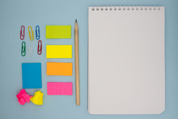 Fixed concept, flat top view Photo of pencils, stationery and notepad on a blue abstract background with copy space, minimal style.