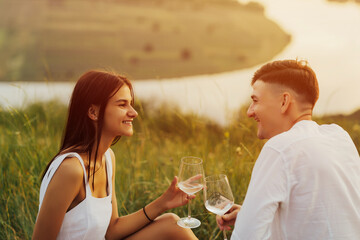 Romantic picnic on the beach. Summer beach picnic at summer sunny day. Young couple looking at each other at weekend picnic  at nature with white wine and fresh fruit.
