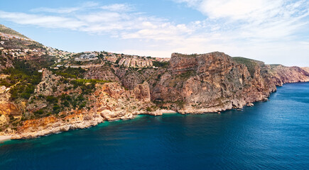 Aerial photo drone point of view picturesque Cala del Moraig in Benitachell coastal town. Bright turquoise waters bay of Mediterranean Sea white sandy beach, huge cliffs coastline. Costa Blanca. Spain