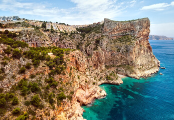Aerial photo drone point of view picturesque Cala del Moraig in Benitachell coastal town. Bright turquoise waters bay of Mediterranean Sea white sandy beach, huge cliffs coastline. Costa Blanca. Spain