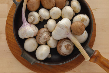 Mushroom and garlic in cast iron pan on wooden board