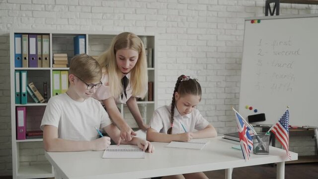 young teacher helping pupil learning and explaining mistakes. Teacher between two students,. Tutoring