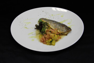 Fried fish with slices of orange and leaves of basil on white plate. Close-up