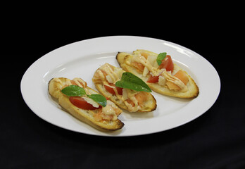 Sandwiches with redfish, basil, tomato, and cheese on a white plate