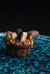 muffins stuffed with delicacy and decorated with chocolates and different sweets on blue plate with black background