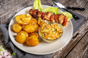 Shish kebab served with roasted potatoes and salad.