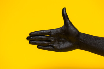 Elegant female hand with a black paint on it  isolated on a yellow background. Free space for text