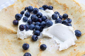 Homemade pancake with blueberries and curd cream closeup