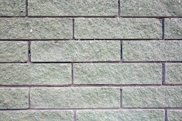 The texture of a light green brick wall in the morning light