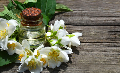 Jasmine essential oil in a glass bottle and fresh jasmin flowers on old wooden background.Aromatherapy,spa or wellness concept.Selective focus.