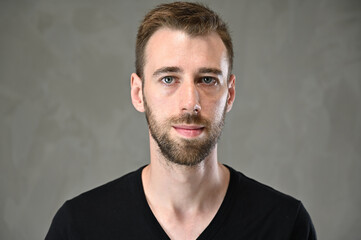 Close-up photo of a handsome caucasian man with a beard in a studio on a gray background