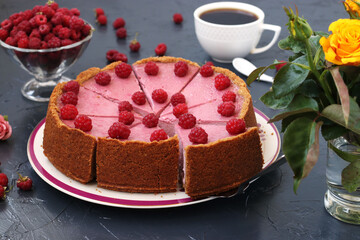 Chopped homemade raspberry cheesecake in portions on a plate, located on dark background, Closeup, Horizontal format