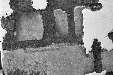 A ragged brick wall. Peeling putty, cement, paint. Unloaded wall, preparation for repair. Texture, cracked, chipped.