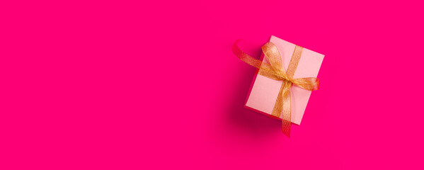 Banner with pink background with a beautiful box for a gift. A place for text. View from above.