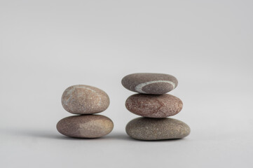 Two simplicity stones cairns isolated on white background, group of light five gray white pebbles built in two towers