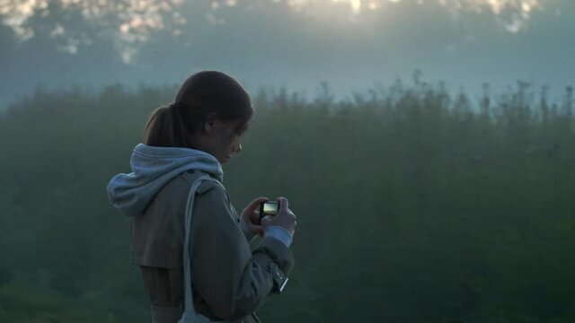 Girl take photos of morning fog in the grassland