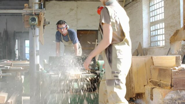 Team of carpenters planning wood using a machine
