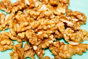 Walnut kernels are piled up in a close-up on a turquoise background.