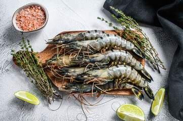 Black raw tiger prawns, shrimps on a cutting board. Gray background. Top view