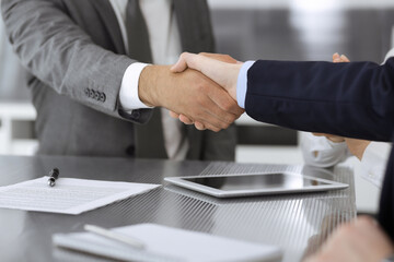 Handshake as successful negotiation ending, close-up. Unknown business people shaking hands after contract signing in modern office