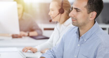 Fototapeta premium Business people working together in modern office. Happy smiling adult businessman using pc computer with colleagues. Teamwork and partnership concept