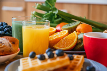 Continental breakfast of waffles with blackberries, bread, fresh fruit, coffee, narnaja juice, green juice and crosaint