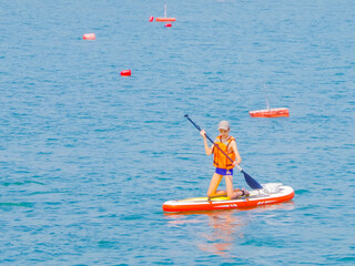 a young rider on a board for Sap surfing rakes a wave with a paddle, the concept of an active...