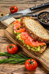 Healthy sandwich with avocado and salmon.  Wooden background. Top view