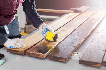Brown color stain painting on wooden table or fence or wall, or flour, use for home decorated. House renovation. Half - painted surface. Hand holding brush. Background with copy space.