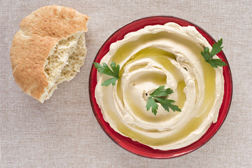 Hummus plate and pita bread on cotton fabric background.