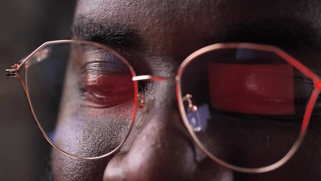 Smiling dark-skinned man seeing sale advertisement in online store while shopping on the internet. African american male making purchases online on laptop, discount advertising reflected in glasses
