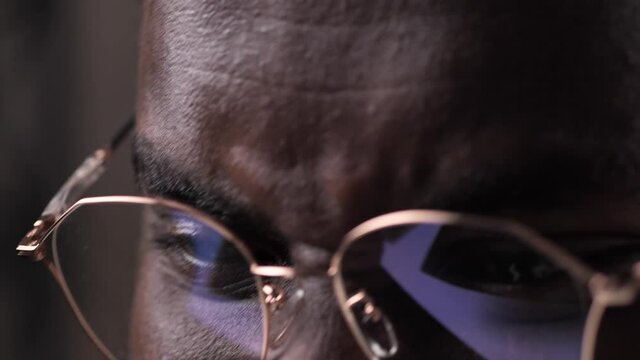 Happy african american male looking at Black Friday advertisement while shopping in online store. Joyful dark-skinned man purchasing online, black Friday's advertising reflected in glasses