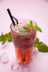 Mojito with strawberries, raspberries and mint. On the pink table.
