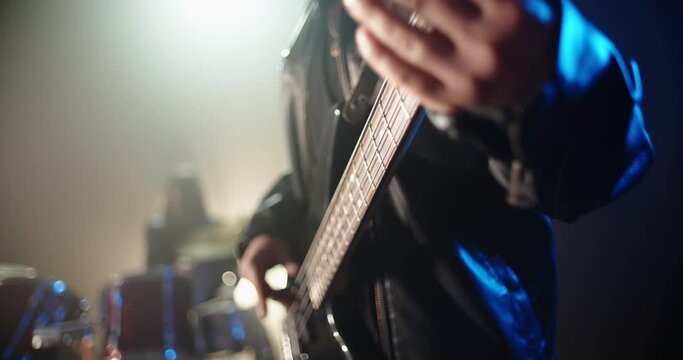 Closeup shot of cool rock bass player making a solo with band mate drummer on background - rock music concept 4k footage