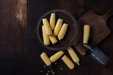 Green corn with sieve and grater on a rustic wooden table. Top view.