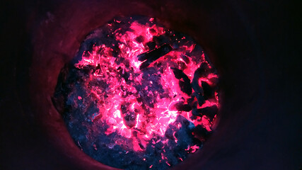 Burning embers at the bottom of a metal barrel.