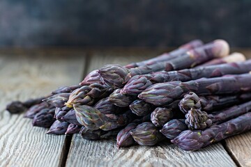 Fresh bunch of purple asparagus on a wooden background. Raw food concept.