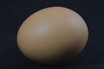 Brown egg upon a black background.