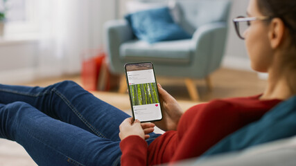 Young Woman at Home Lying on a Couch using Smartphone Scrolling Through Sotcial Media Feed, Doing Swiping, Scrolling Gestures.