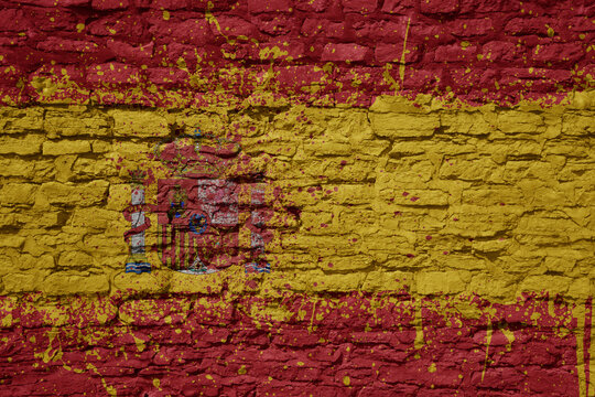 painted big national flag of spain on a massive old brick wall © luzitanija