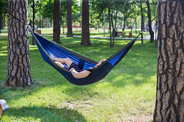 Young guy has a rest in summer in a hammock