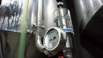 A pressure sensor connected to a factory tank is running to prevent the equipment from a pressure overload. A bottom view slow motion close up