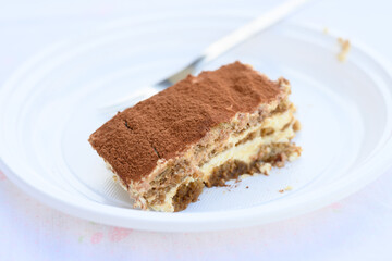 Porzione di dolce tiramisù servita in un piatto usa e getta 