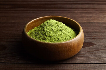 Wheatgrass or barley grass powder in wooden bowl on dark background.